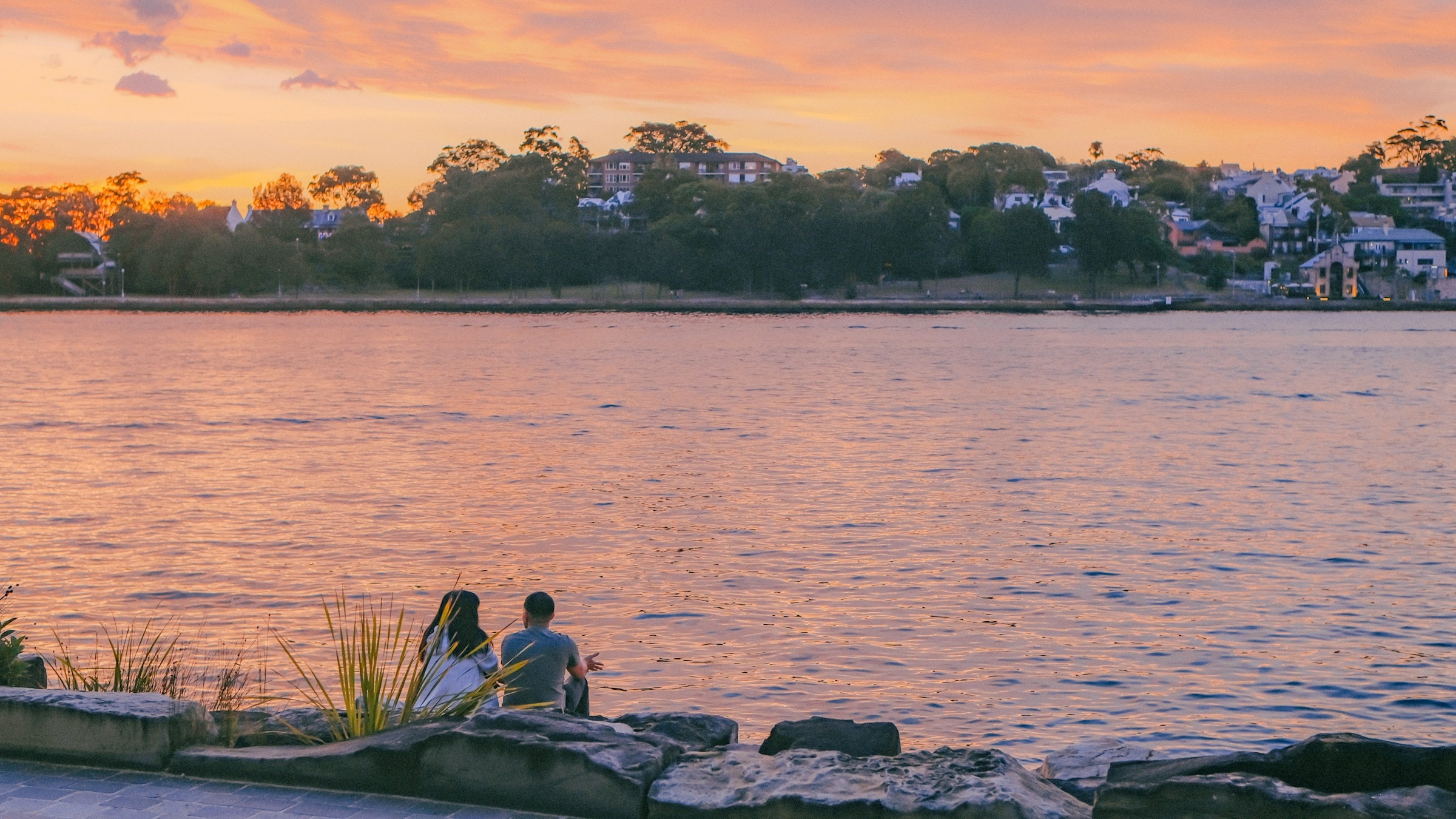 A couple in quiet conversation at golden hour, looking out over calm water, freedom, time together and the life retirement makes possible